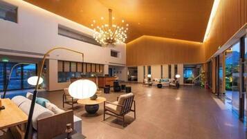 A spacious lobby with a modern chandelier, seating areas, and large windows.