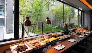 A buffet setup with various food items and a view of greenery outside. - Huiting Yunju Hotel Yanshan Guilin (Guilin)