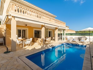 A poolside area with a clear blue pool, outdoor seating, and a covered patio. - Villa Occitania by Interhome (Cala Murada)