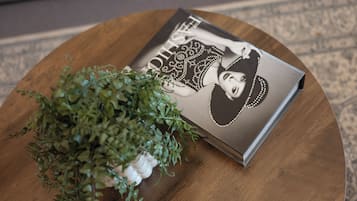 A round wooden table with a magazine featuring a woman's portrait and a small potted plant.