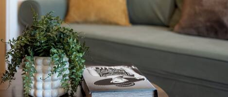 A living room with a green sofa, a round wooden coffee table, a potted plant, and a book.