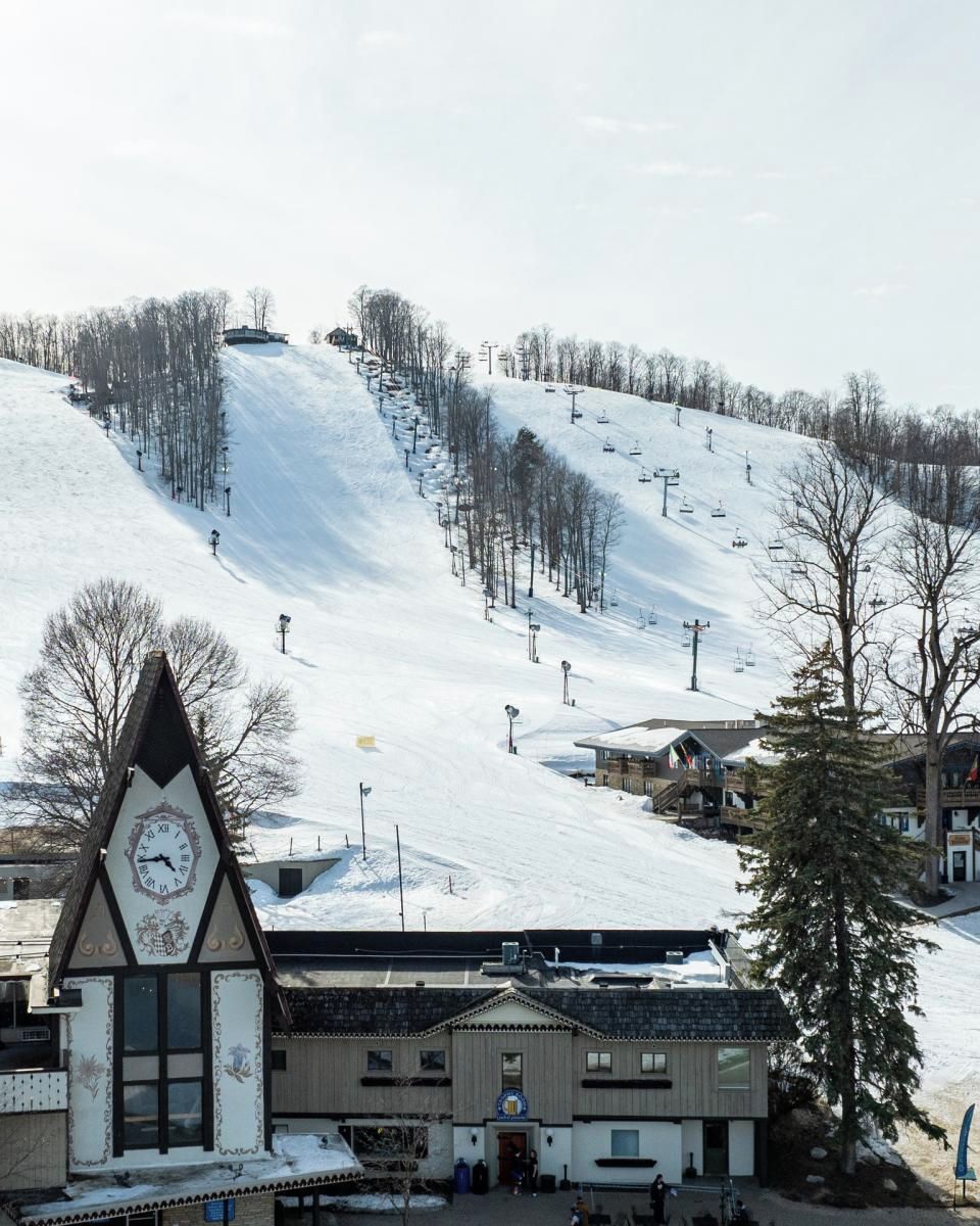 A ski resort with a clock tower, a ski lift, and a building with a sign.