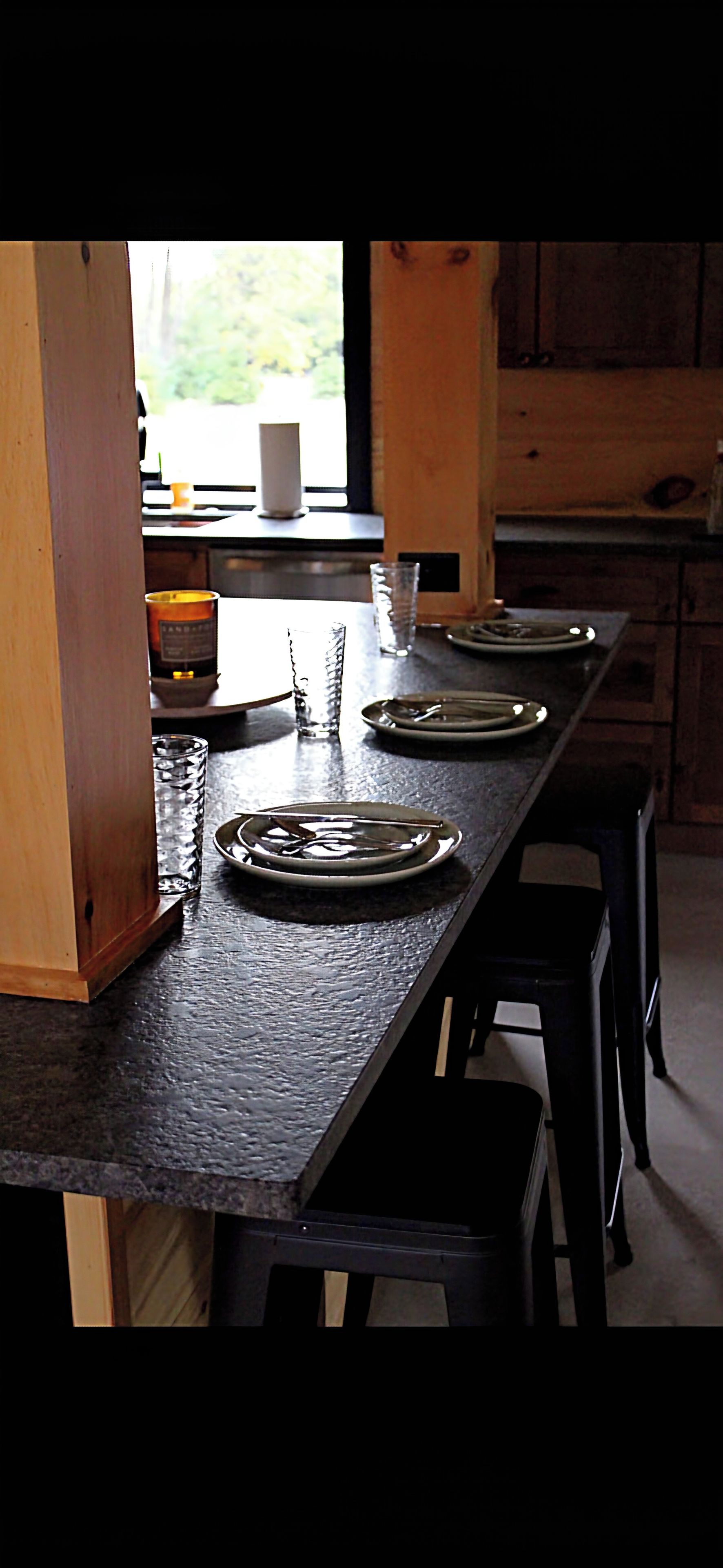 Een eettafel met borden, bestek, een kaars en een glas.