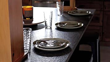 Een eettafel met borden, bestek, een kaars en een glas.