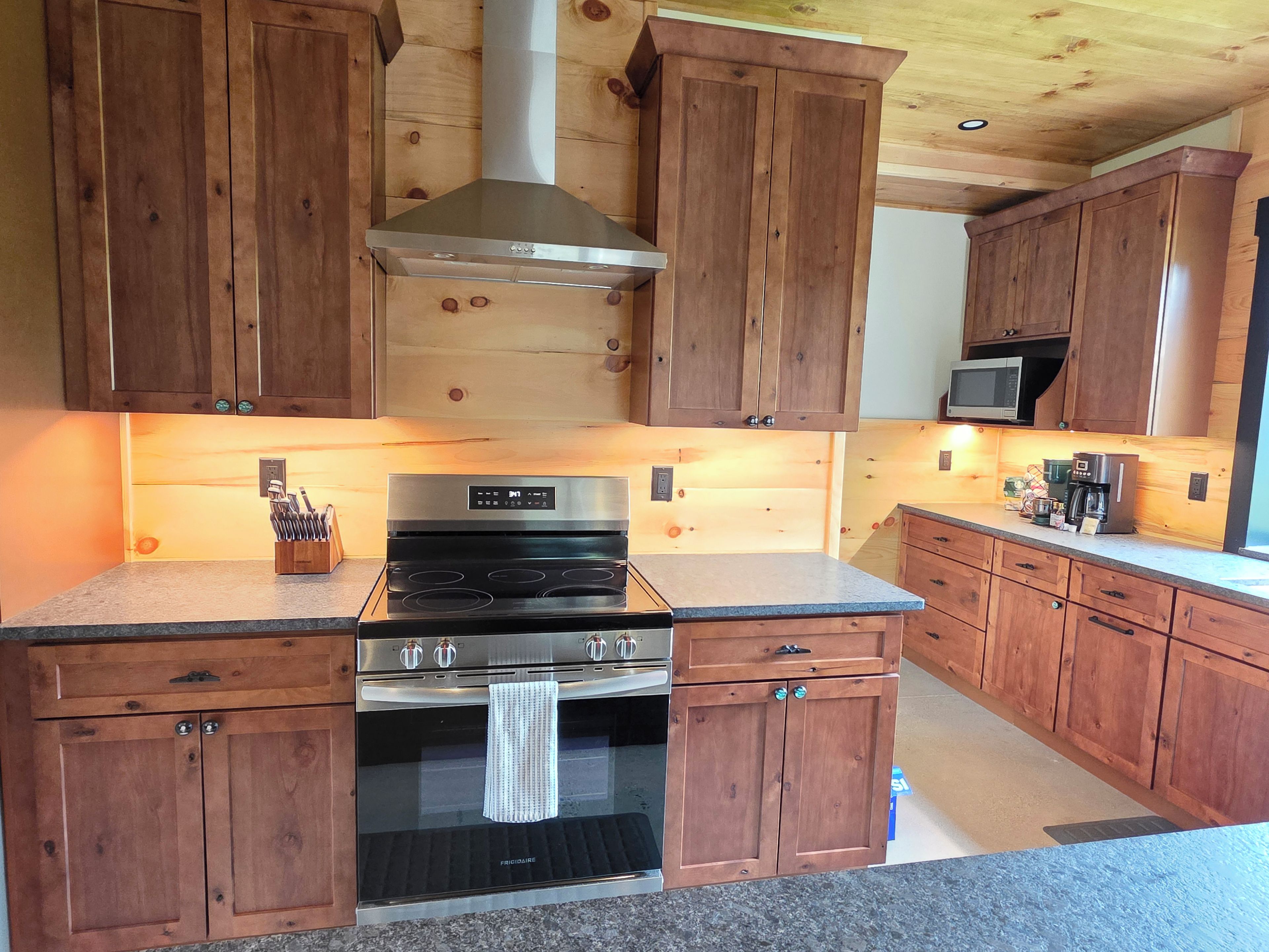 A kitchen with wooden cabinets, a stainless steel range hood, a built-in oven, and a microwave.