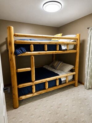A bunk bed with a wooden frame, a ceiling light, and a patterned carpet. - Schuss Haus • Modern Chalet • Hot Tub • Ski • Golf • A/C (Bellaire)
