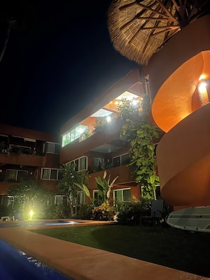 A hotel with a pool, multiple balconies, and outdoor lighting. - 3-bedroom condo 1 Block from Playa La Ropa (Ixtapa Zihuatanejo)