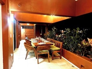 A dining area with a long wooden table set for a meal, surrounded by wooden chairs with cushions. - 3-bedroom condo 1 Block from Playa La Ropa (Ixtapa Zihuatanejo)