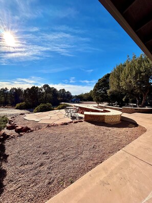 A patio area with a fire pit, outdoor seating, and a view of a river and trees. - Sedona Luxury 5-Bedrm Oasis, Pool-Spa, Yoga, Views (Sedona)