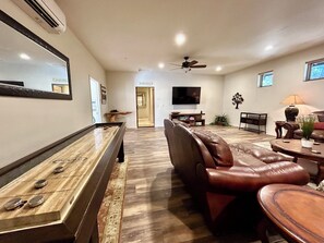 Un salon avec une table de billard, un canapé en cuir et un téléviseur.