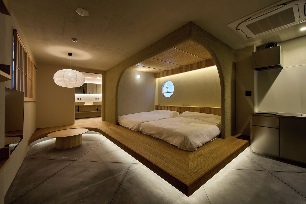 A modern bedroom with a built-in bed, a round mirror, and a small bedside table.