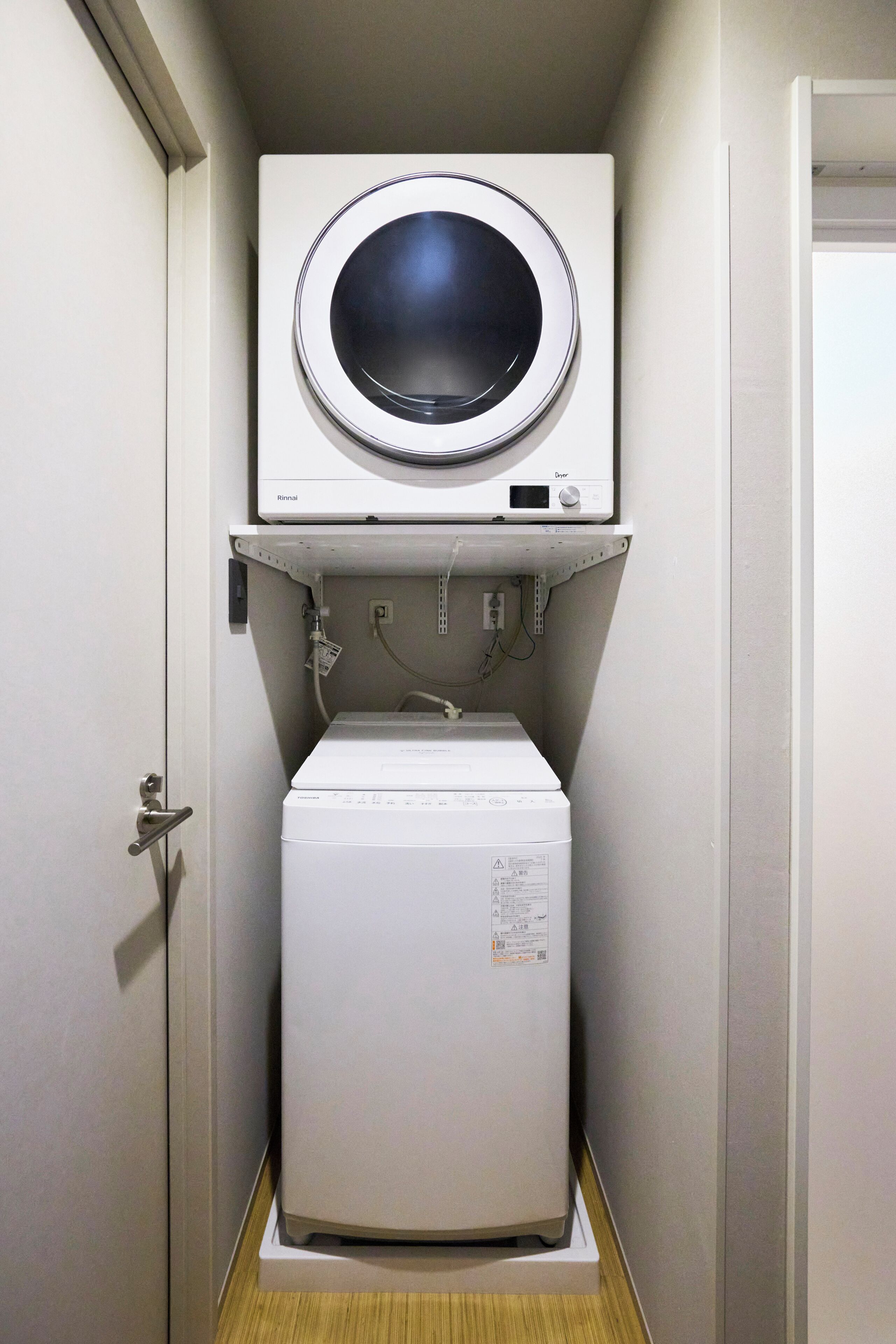 A compact laundry room with a front-loading washer and a top-loading dryer.