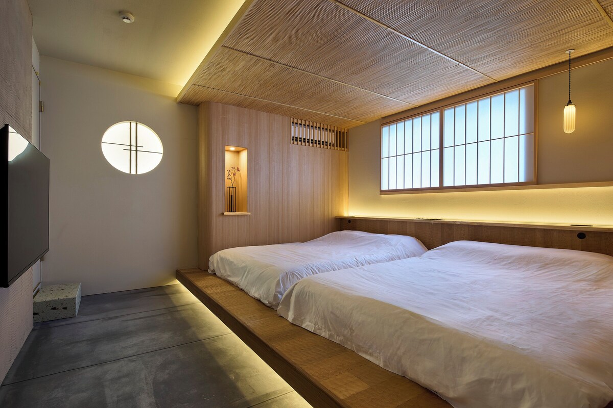 A hotel room with two beds, a large window, and a ceiling with a wooden pattern.