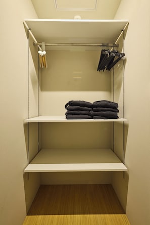 A walk-in closet with shelves, a hanging rod, and a wooden floor.