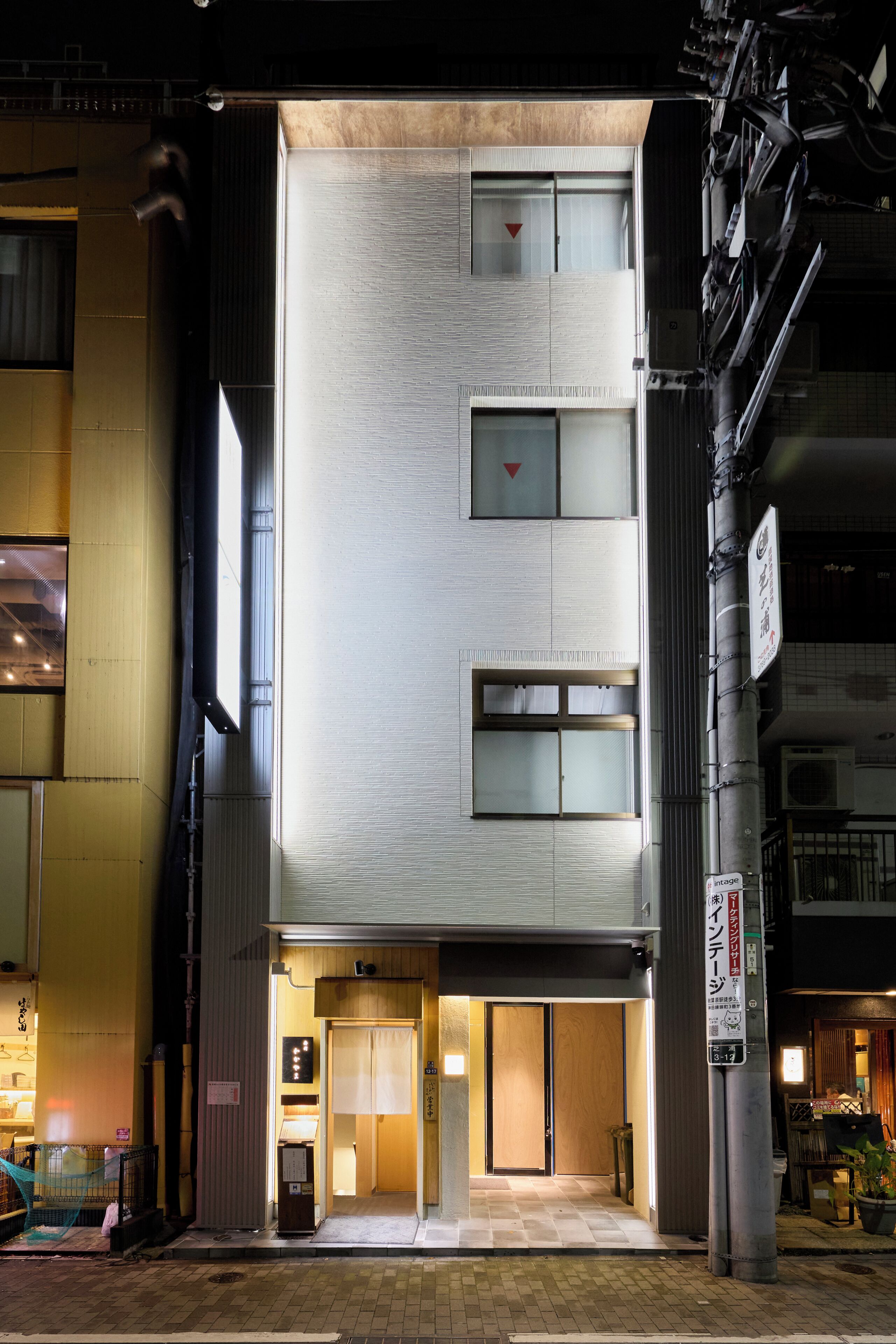 A modern building with a flat facade, multiple windows, and a ground-level entrance.