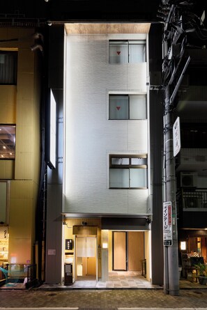 A modern building with a flat facade, multiple windows, and a ground-level entrance.