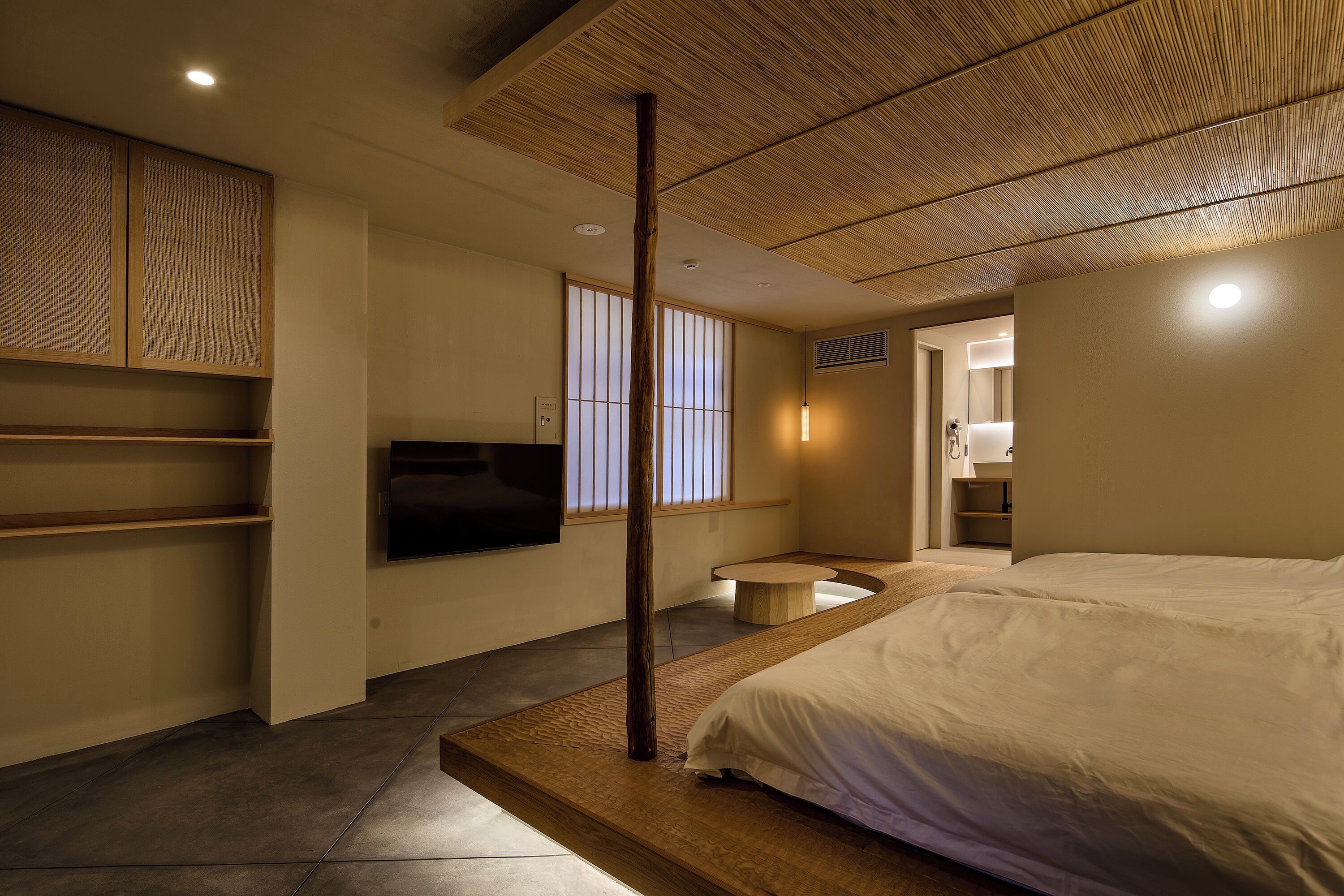 Une chambre moderne avec un grand lit, une télévision et un plafond en bois.