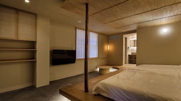 A modern bedroom with a large bed, a television, and a wooden ceiling.