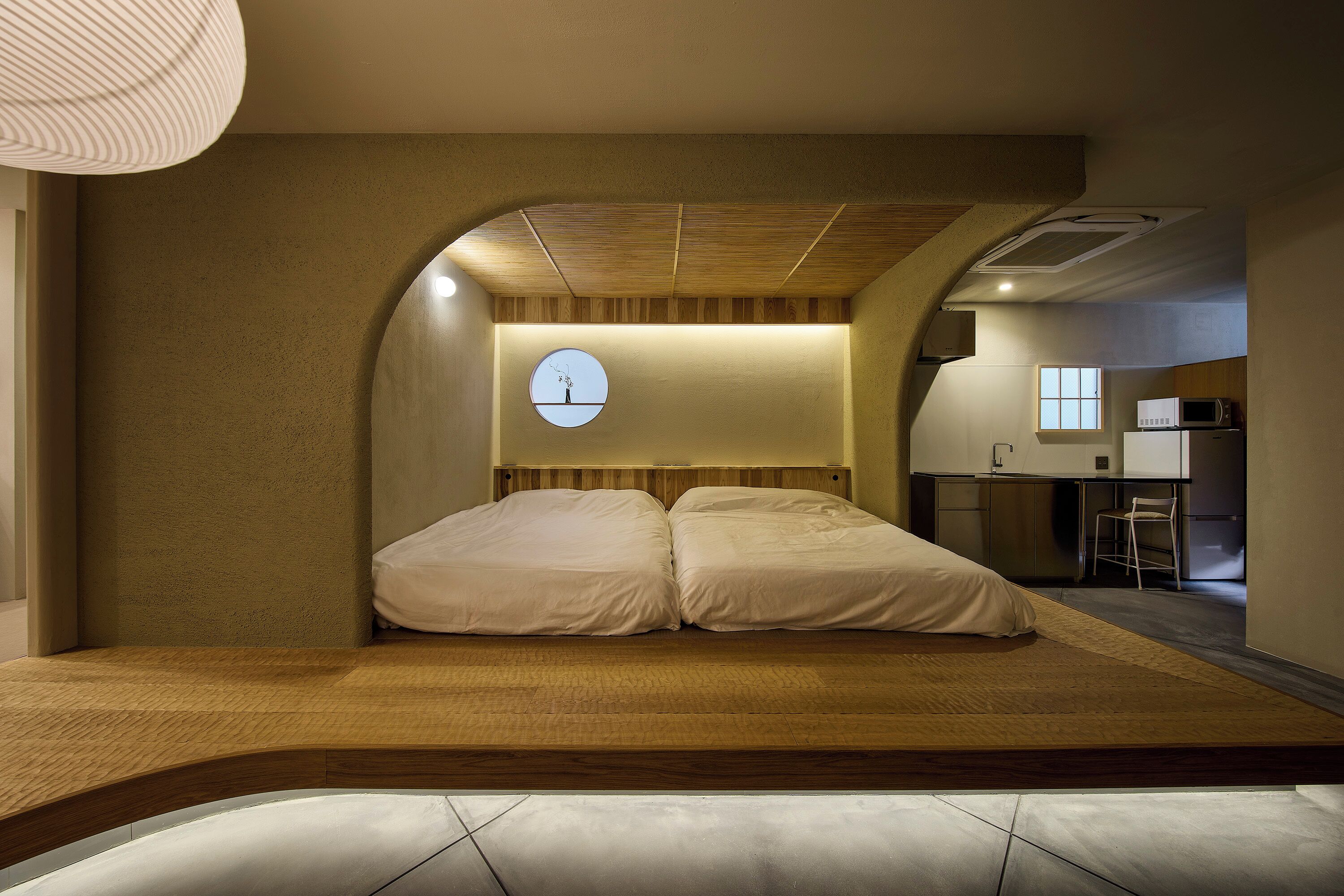 Una camera da letto con un letto, una decorazione circolare a parete e una piccola cucina sullo sfondo.