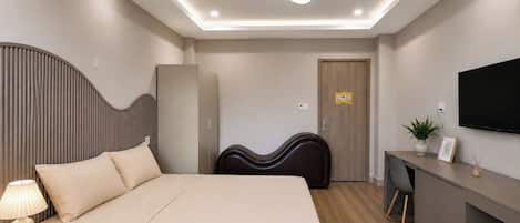 Une chambre d’hôtel moderne équipée d’un lit, d’une table de chevet, d’une lampe, d’une armoire, d’un bureau, d’une chaise, d’un téléviseur et d’une plante en pot.