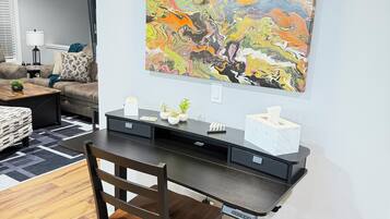 A modern home office with a desk, chair, and a colorful abstract painting on the wall.