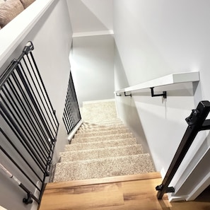 A staircase with a wooden handrail and a black metal railing.
