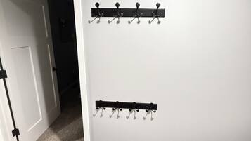 A hallway with a white door, a coat rack, and a wooden floor.