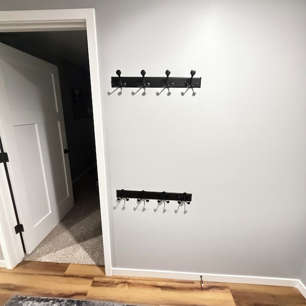 A hallway with a white door, a coat rack, and a wooden floor.
