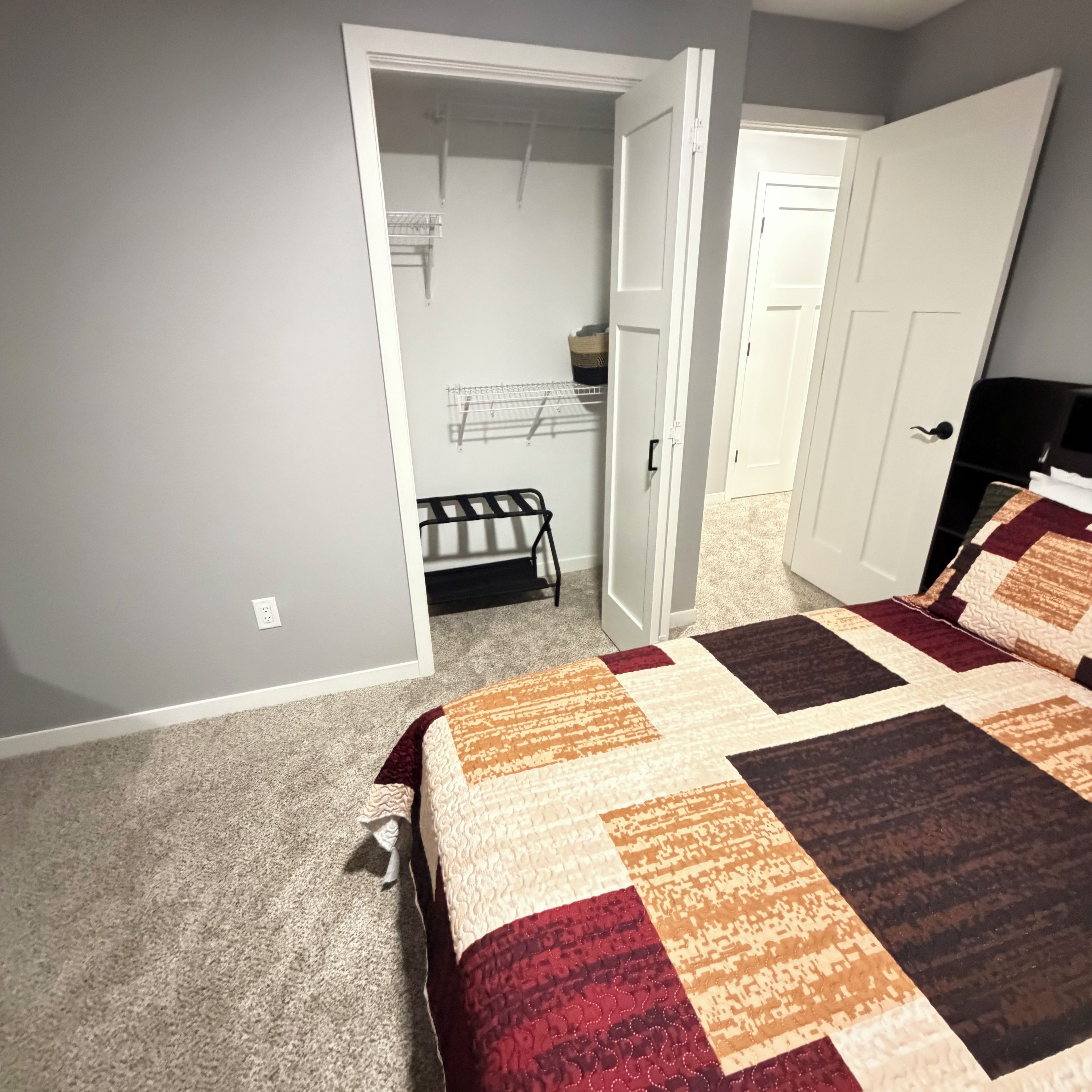 Une chambre à coucher comprenant un lit, une armoire et une porte donnant sur une autre pièce.