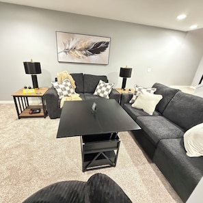 A modern living room with a grey sofa, a black coffee table, and two side tables with lamps.