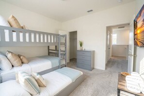A bedroom with bunk beds, a dresser, and a painting.