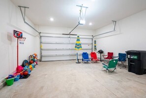 A garage with a basketball hoop, colorful storage bins, and a variety of chairs. - Pool Jacuzzi | Gated community | 6 Min to Beach (Palm Coast)