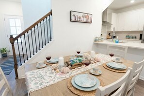 A dining area with a wooden table set for four, surrounded by white chairs. - Pool Jacuzzi | Gated community | 6 Min to Beach (Palm Coast)