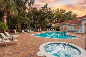 A swimming pool with lounge chairs and a hot tub, surrounded by trees and a building with a tiled roof. - Pool Jacuzzi | Gated community | 6 Min to Beach (Palm Coast)