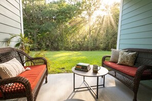 A porch with wicker furniture, a small round table, and books. - Pool Jacuzzi | Gated community | 6 Min to Beach (Palm Coast)