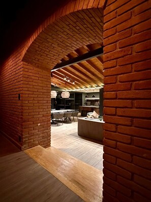 An interior space with brick walls, wooden flooring, and a dining area with chairs and tables. - Casa Chimeneas: Perfect for families—just 10 minutes from downtown Avándaro! (Avandaro)