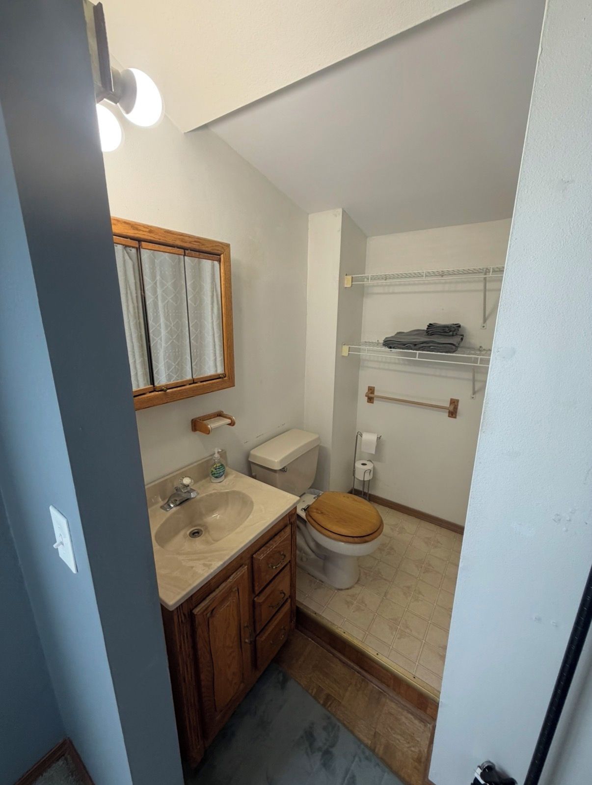 A compact bathroom with a sink, toilet, and wooden cabinets.