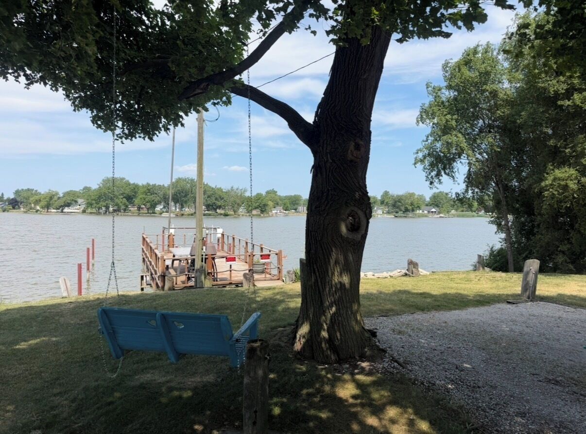 Une balançoire, un banc et une jetée avec un bateau.