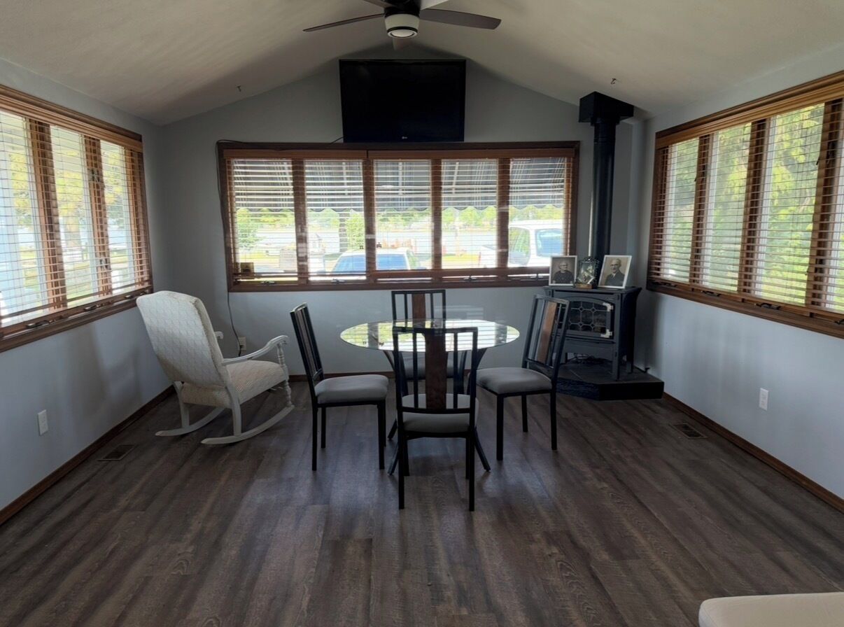 A room with a round table, four chairs, a rocking chair, and a fireplace.