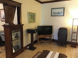 A living room with a television on a stand, a cabinet, and a framed picture on the wall.