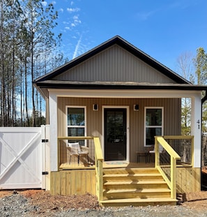 A small, single-story building with a porch, a front door, and a staircase leading to the entrance.