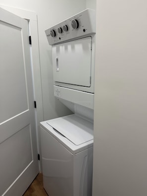 A laundry room with a front-loading washer and dryer, a door, and a control panel with dials.