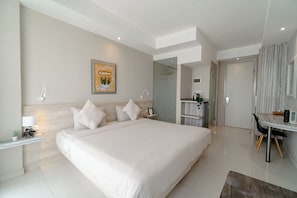 A hotel room with a large bed, bedside tables, a desk, and a shower area.