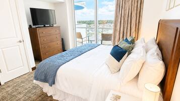 Habitación de hotel con cama, televisor, cómoda y vista a la ciudad.