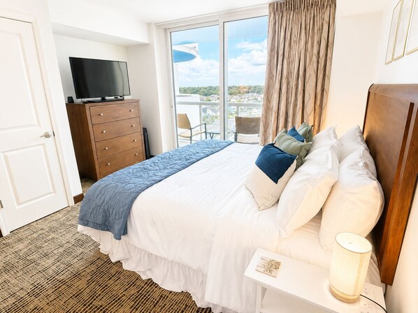 A hotel room with a bed, a television, a dresser, and a view of the city.