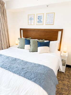 A hotel room with a large bed, a wooden headboard, and two framed pictures on the wall.