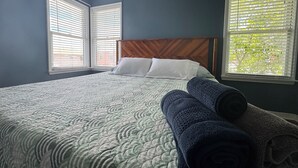 Una camera da letto con un letto, due finestre con persiane e una testiera.
