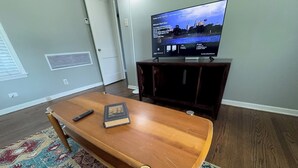Un soggiorno con un tavolino in legno, un telecomando e una televisione su un mobile.