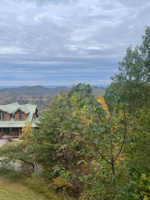 A cabin with a green roof, surrounded by dense foliage and hills in the background. - Blue Hue Horizon Lodge spacious 4-bedrooms/4 bath (9 beds) (Sevierville)