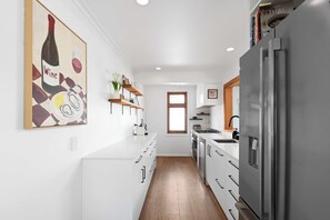 Una cocina moderna con armarios blancos, un refrigerador de acero inoxidable y piso de madera.